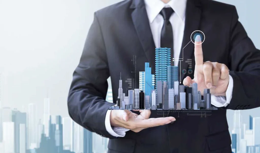 Businessperson in a suit holding a digital city skyline hologram and touching a virtual interface, representing smart real estate technology.